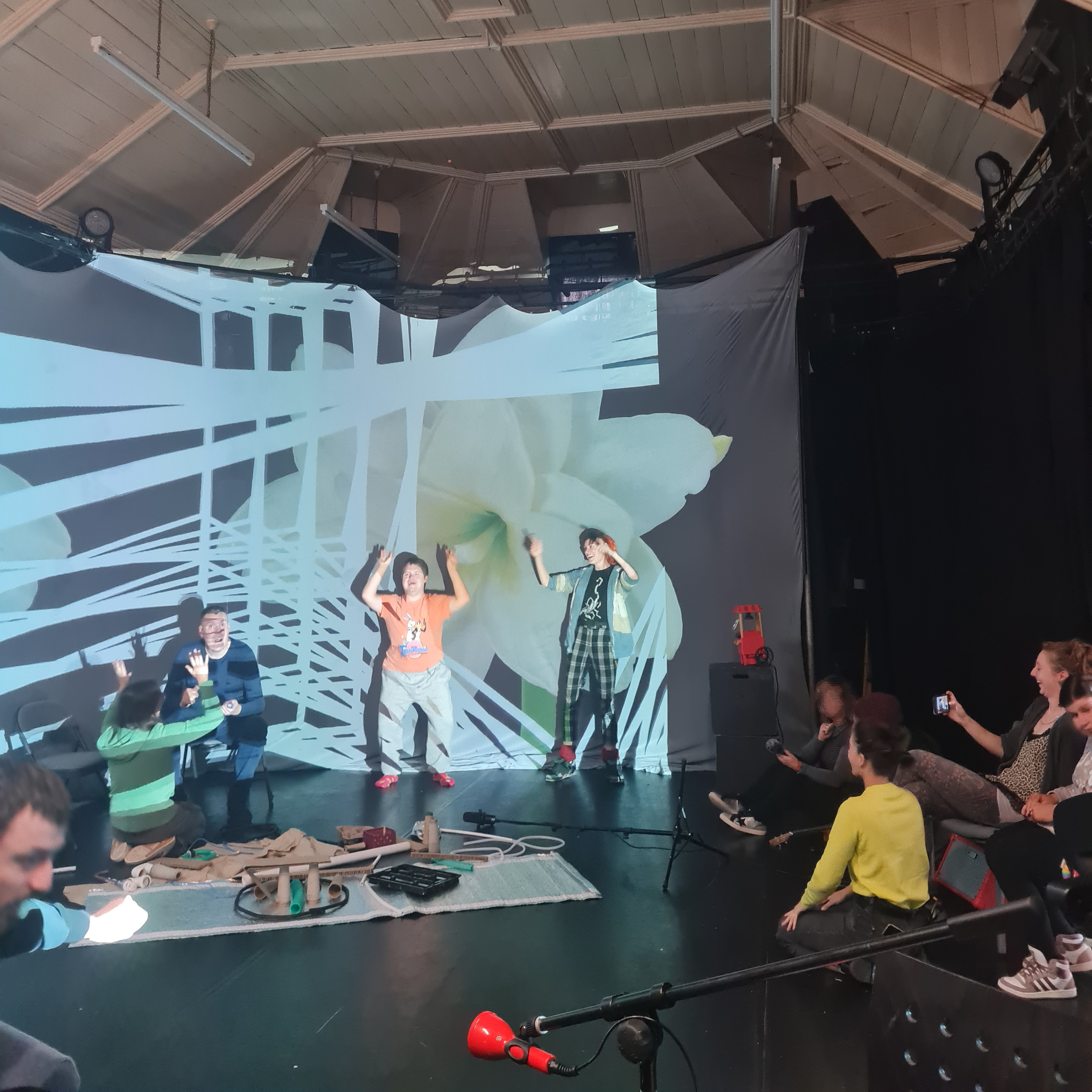 A group of people dancing and moving whilst watching each other having fun. Some cast shadow on a massive projection on fabric.