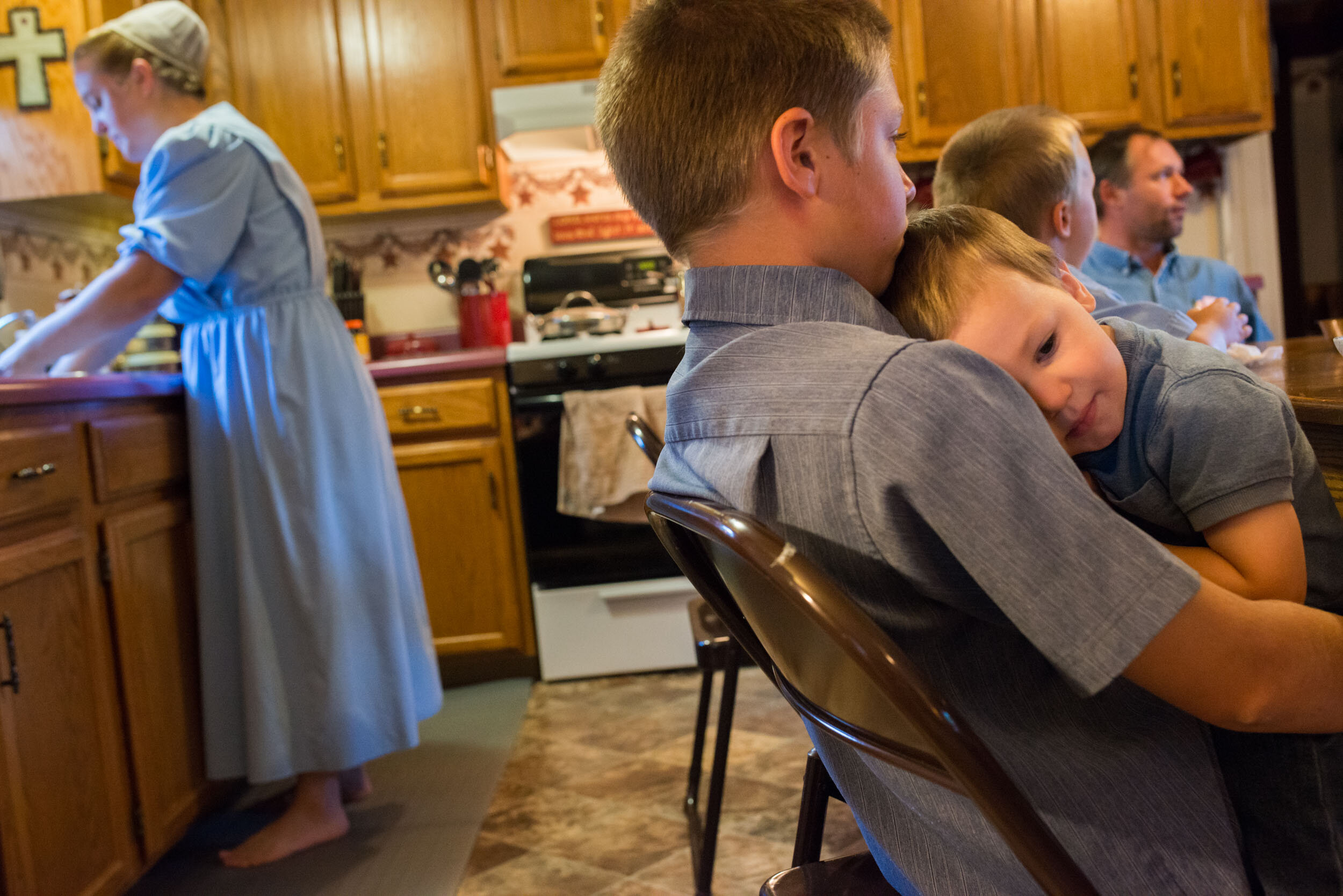 Austin Mast, embraces his brother Colton Mast, at the breakfast table before departing for school. Austin and two other siblings attend a private Mennonite school, while the youngest two children remain at home with Ruthann.