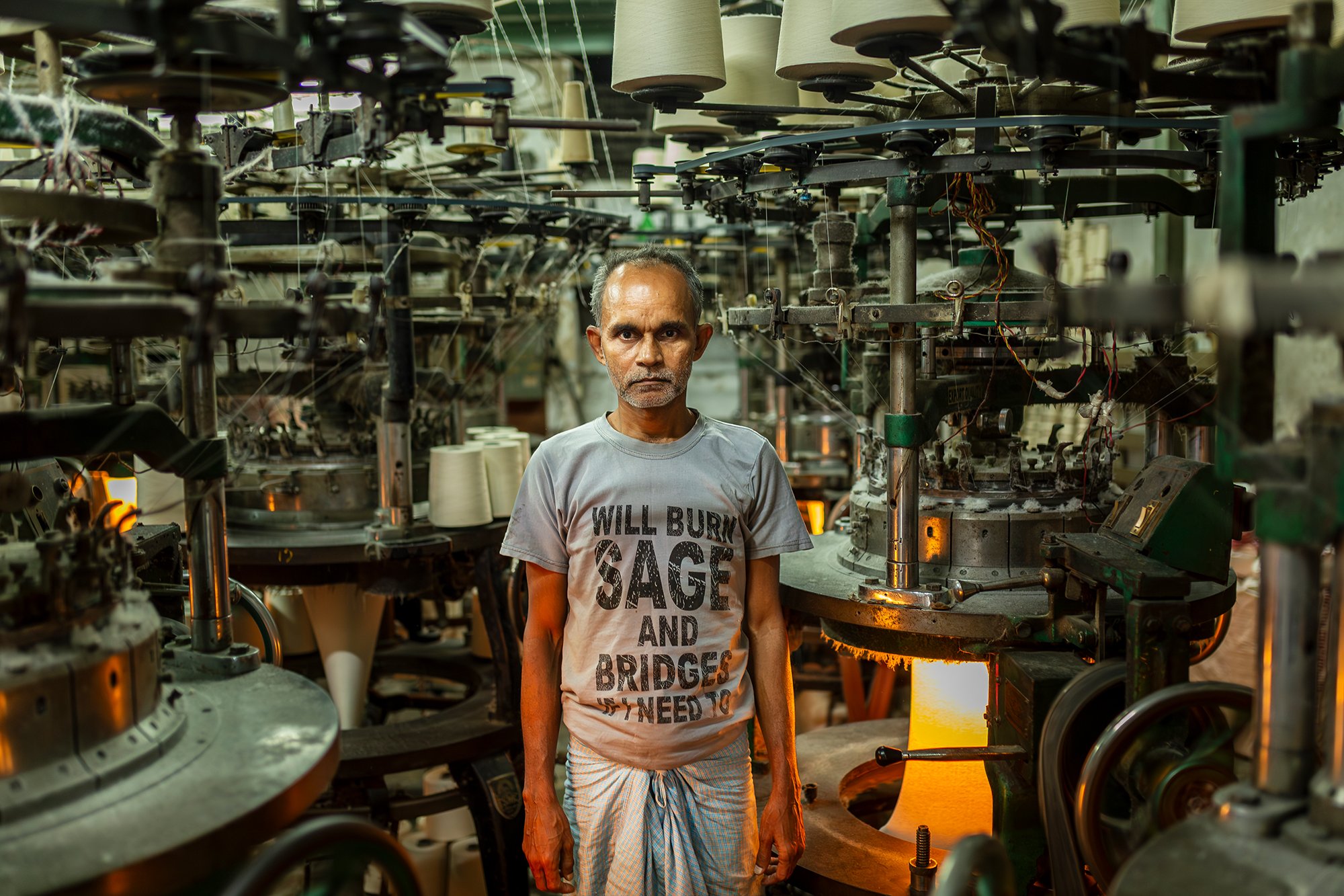 Textile Worker, Kolkata
A textile worker stands among rows of circular knitting machines in a factory in Kolkata. Surrounded by the constant rhythm of machinery, he is part of the process that transforms yarn into fabric.