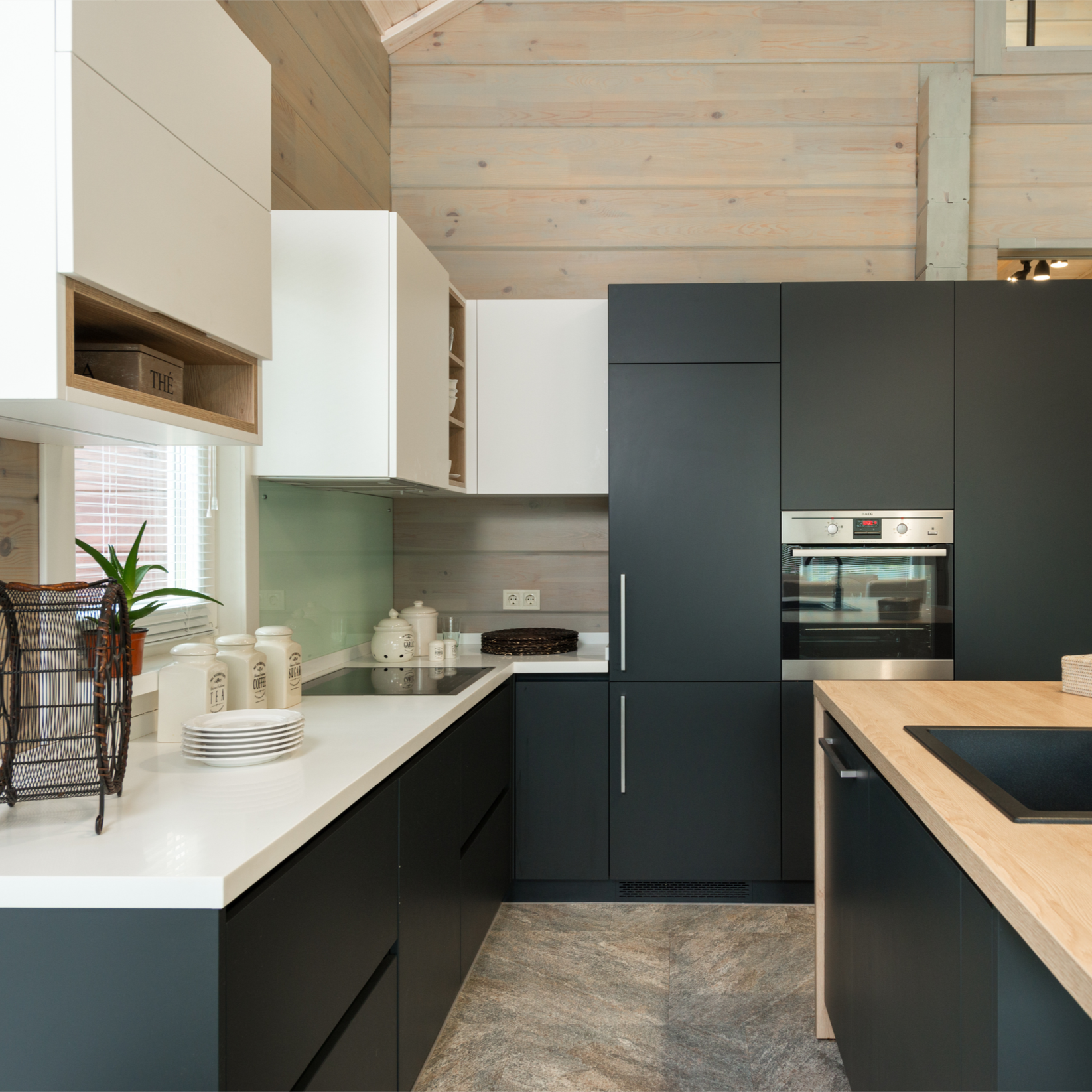 Modern kitchen with black lower cabinets, white upper cabinets, a wooden countertop island, and built-in oven.