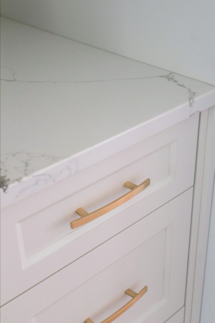 White kitchen cabinet with a marble countertop.