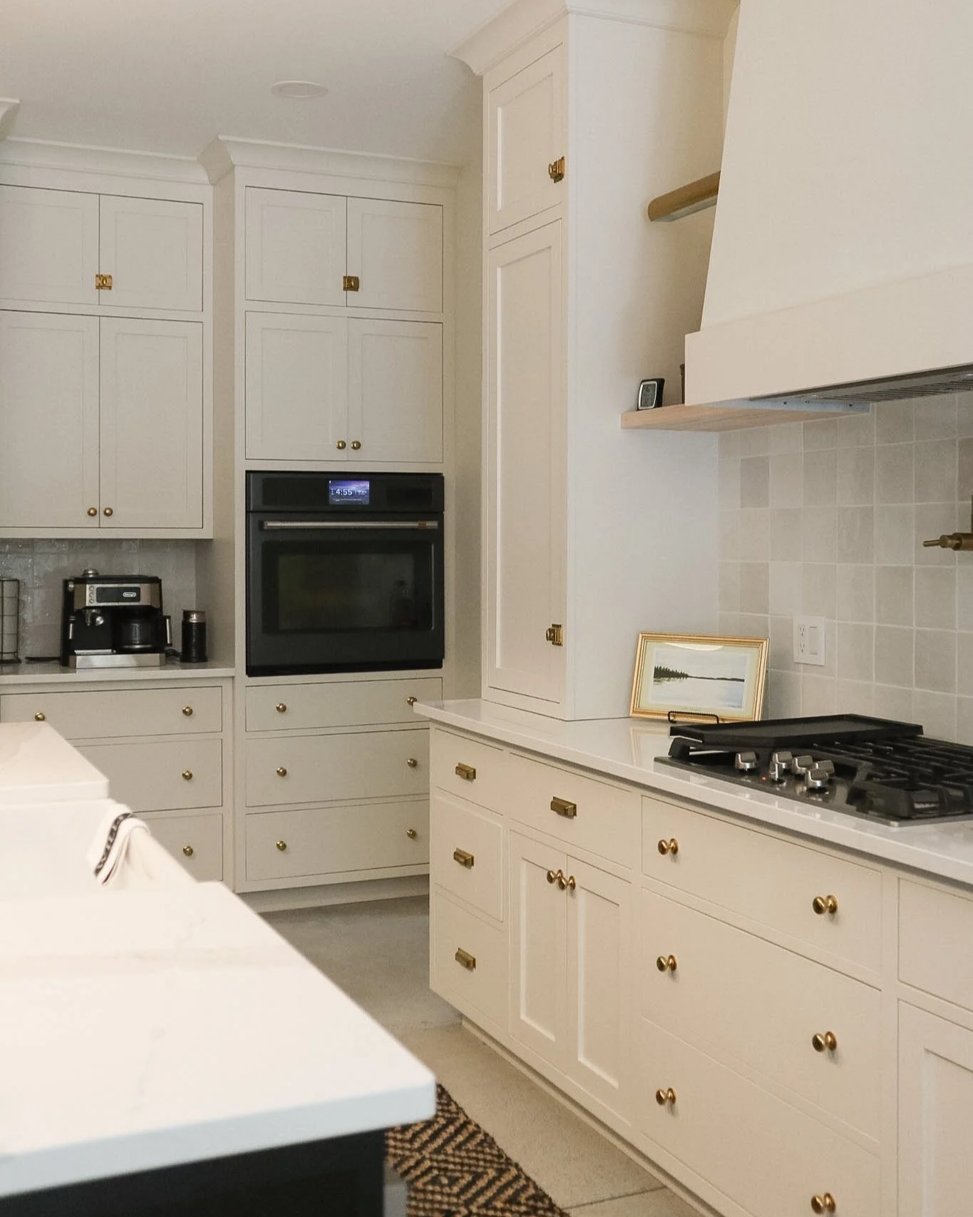 White kitchen with custom face-frame cabinets, a built-in oven, a stove, and small appliances.
