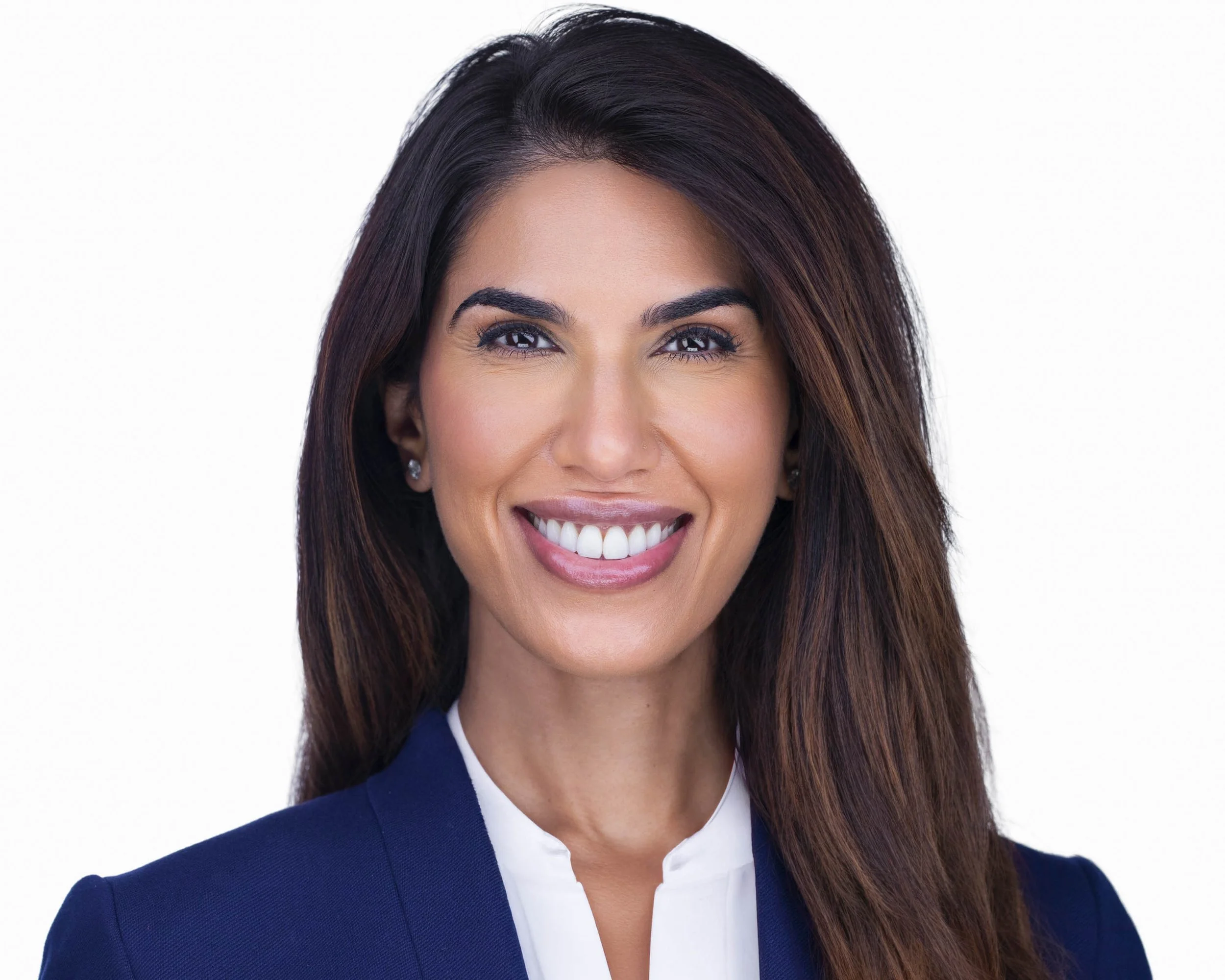 Dallas professional headshots – corporate headshot of woman with long straight dark brown hair, wearing a navy blazer over a white blouse, smiling warmly in Dallas  by Godoy Shots headshot studio with clean white background.