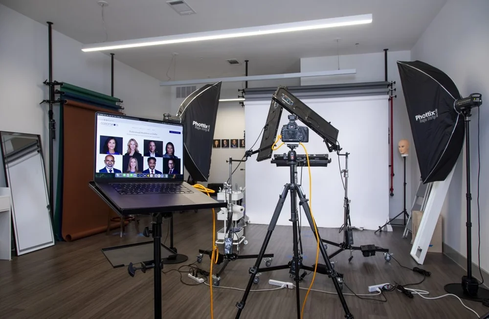 Godoy Shots studio with a headshot lighting setup and a large monitor displaying portraits.