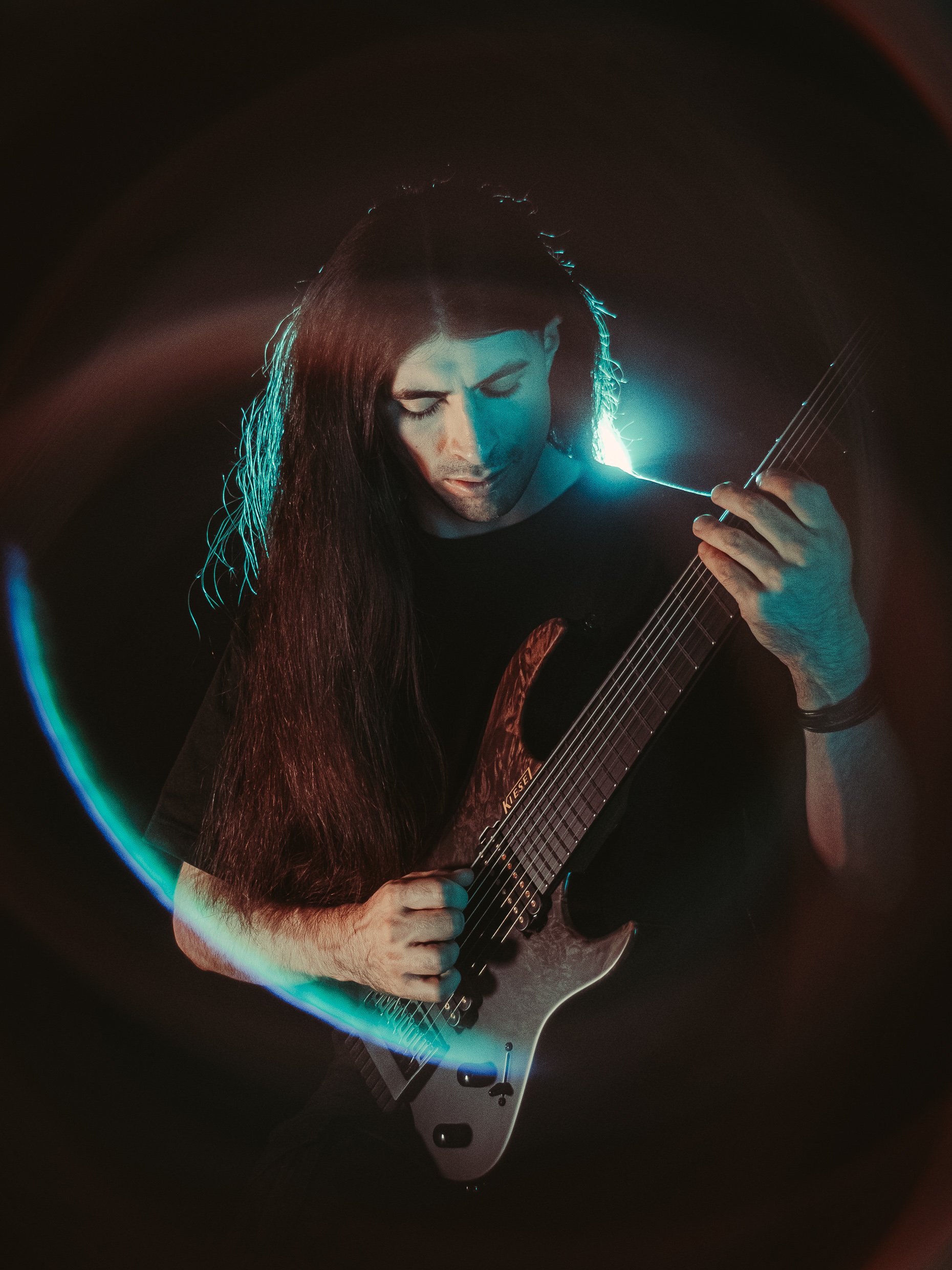 Rafael Trujillo playing guitar, photographed with turquoise stage lighting