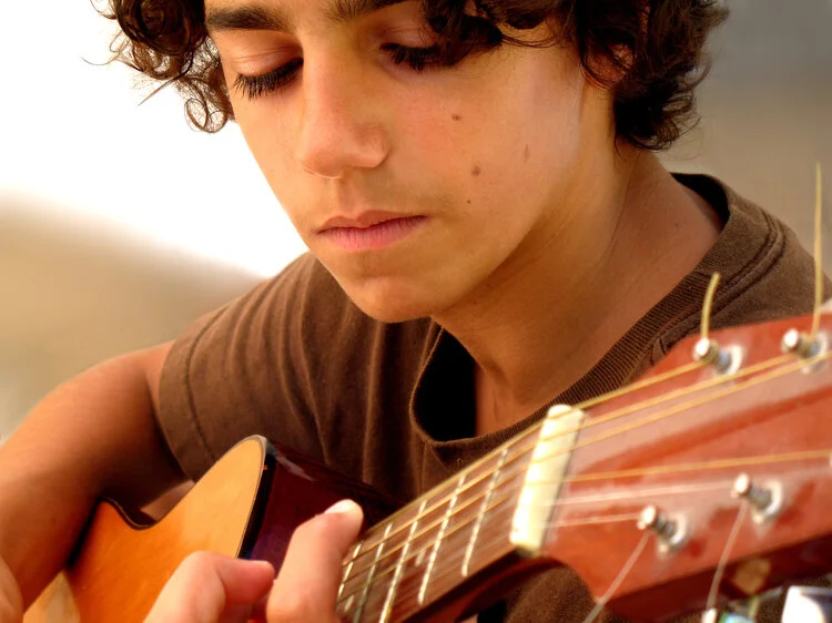 Teenage boy playing the acoustic guitar