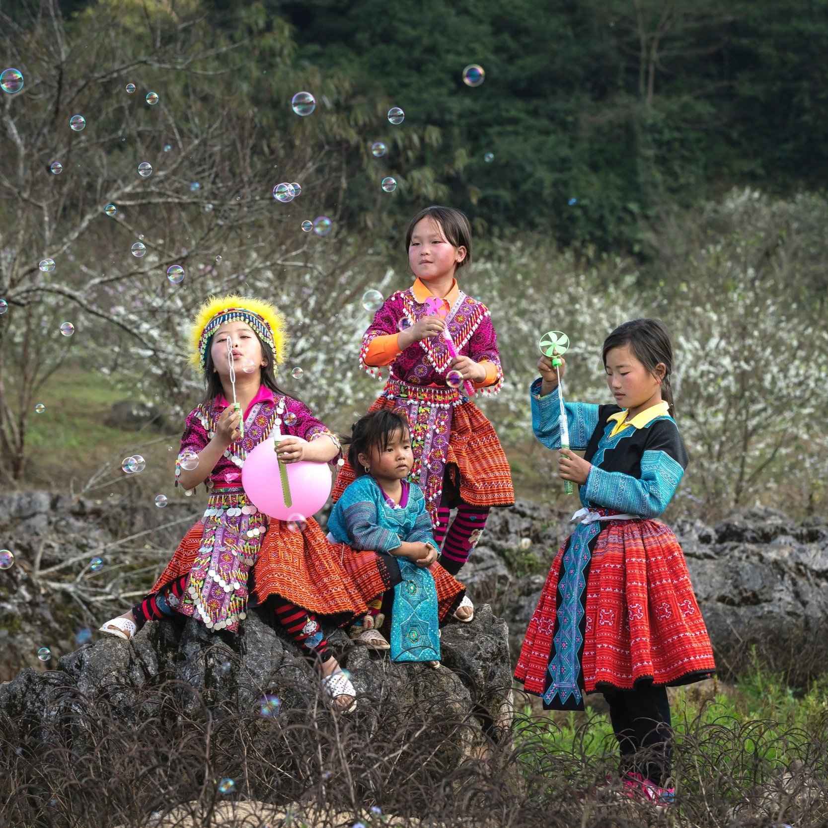 4 girls in the woods, blowing bubbles in traditional Vietnamese clothing