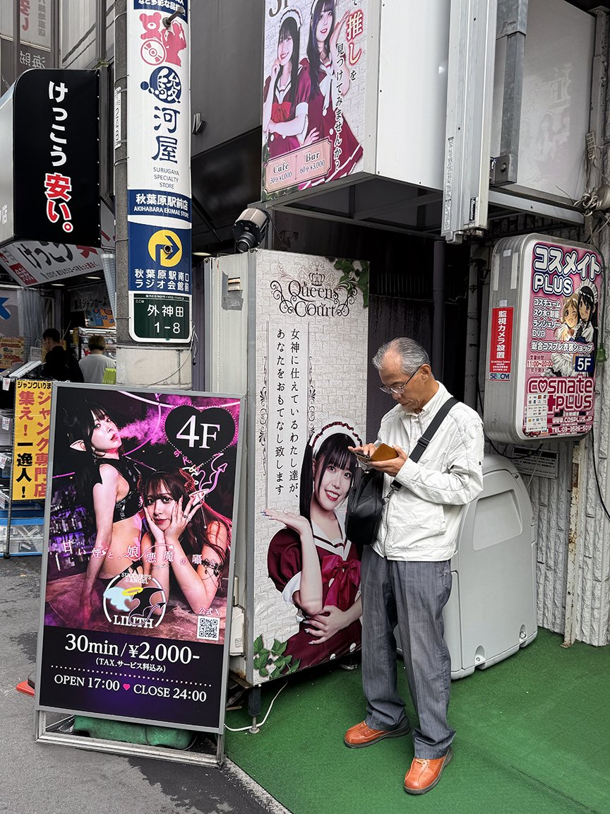 Man looking at phone, Akihabara, 2025