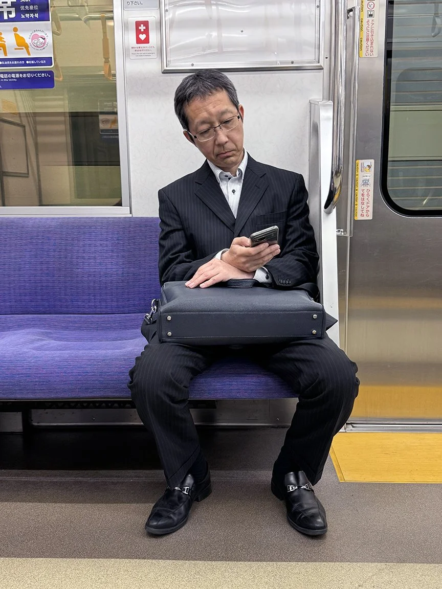 Man looking at phone, Marunouchi Line, 2025