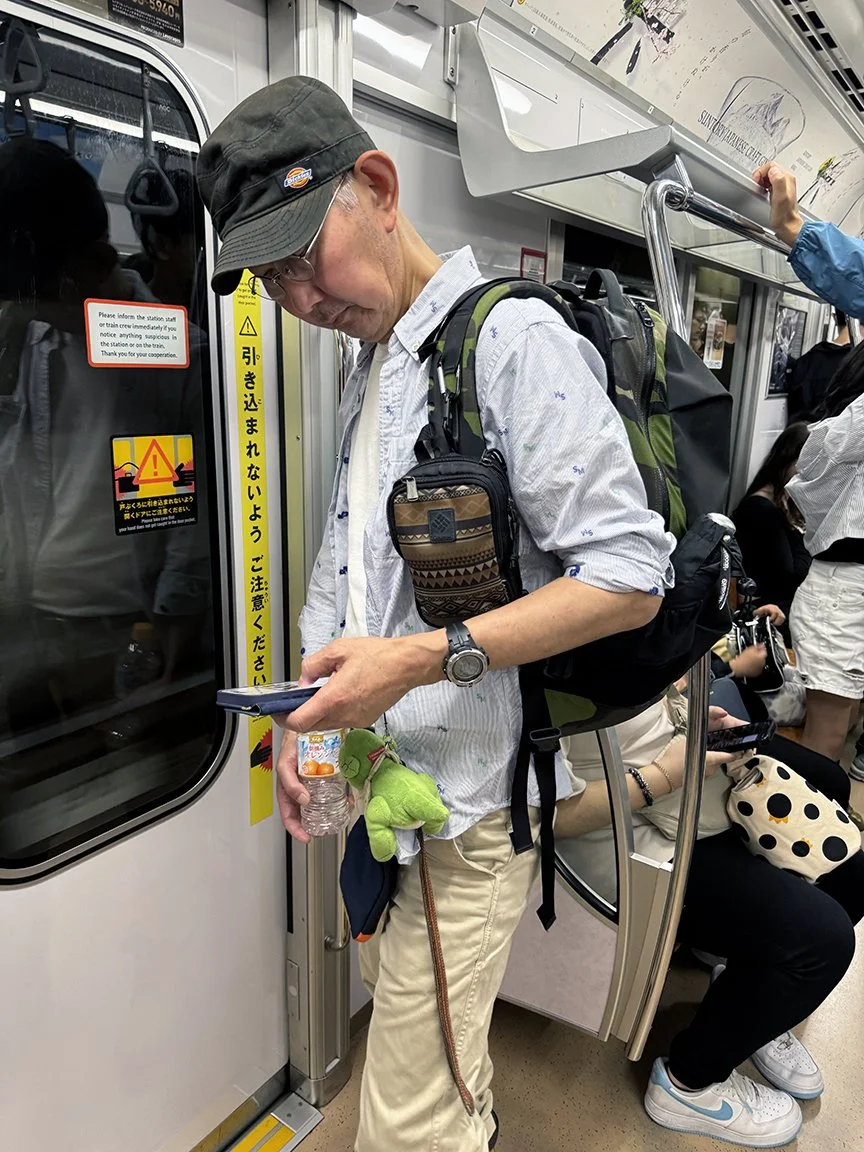 Man looking at phone, Mita Line, 2025