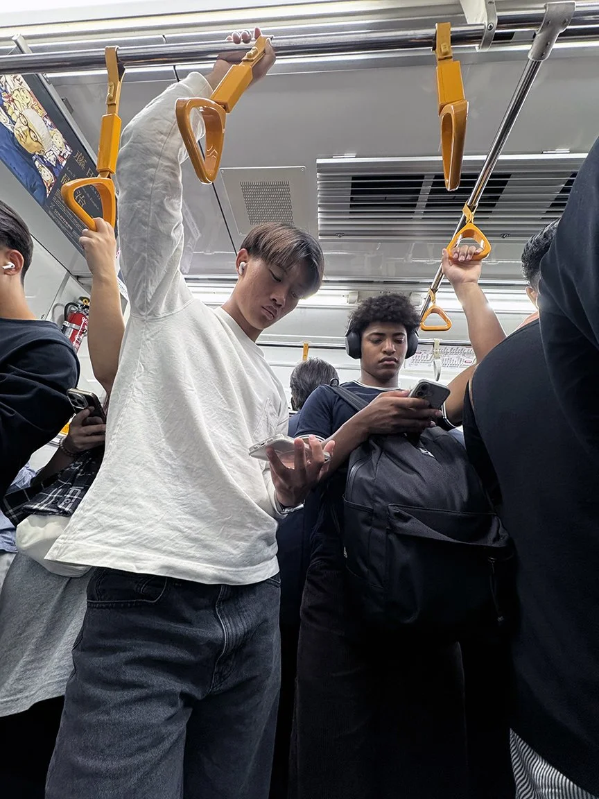 Young men looking at phone, Tozai Line, 2025