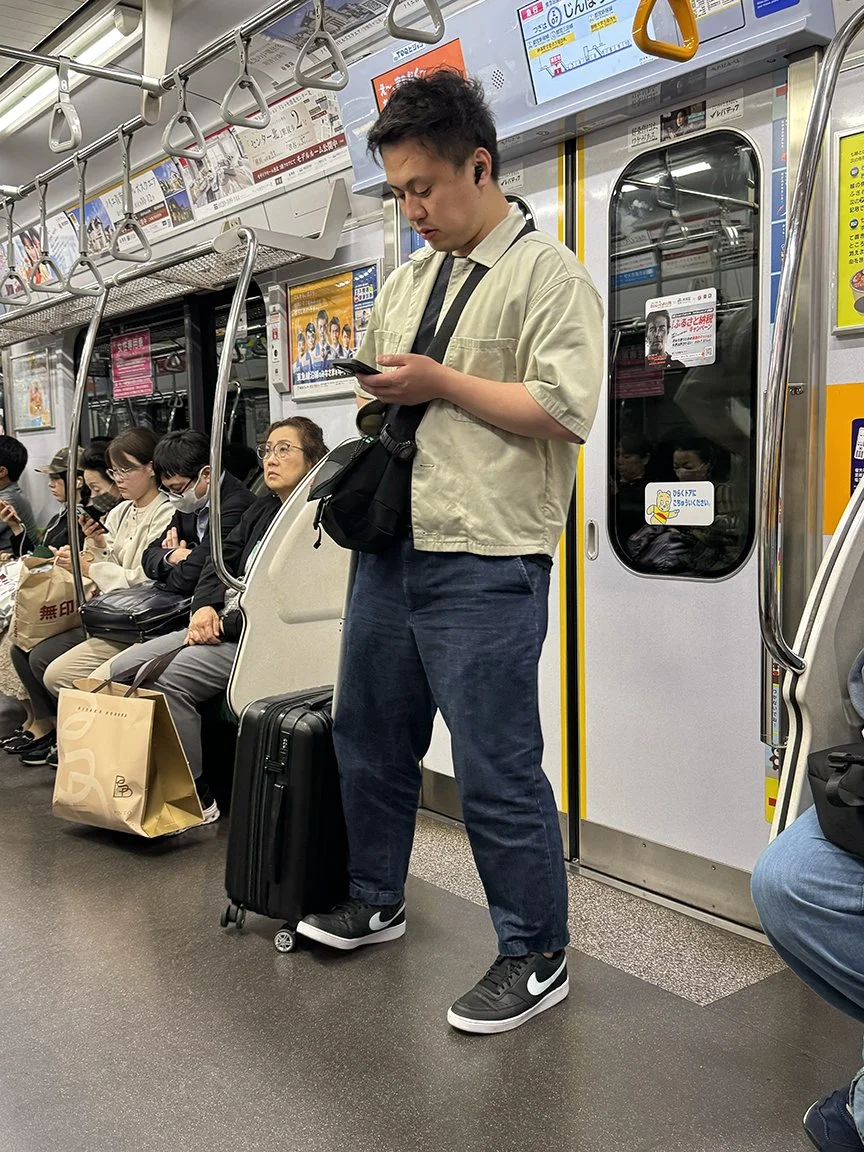 Man looking at phone, Tozai Line, 2025