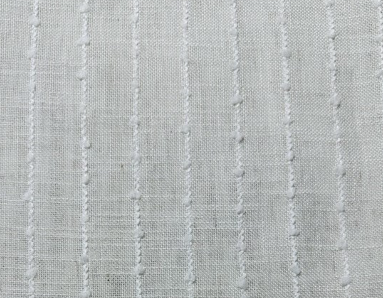 Close-up of a textured white fabric with vertical stitched stripes.