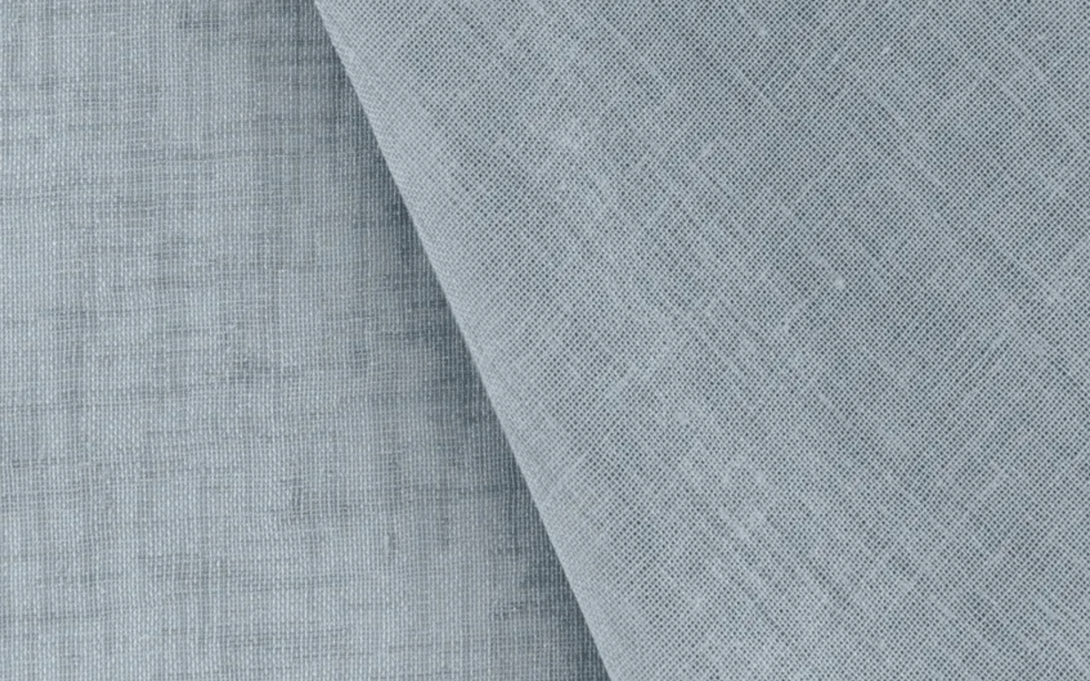 Close-up of a textured fabric surface, showing fine weave and small visible fibers in light gray and blue tones.
