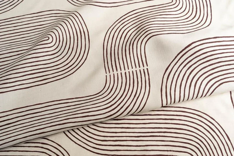 Close-up of fabric with brown curving line patterns on a white background.