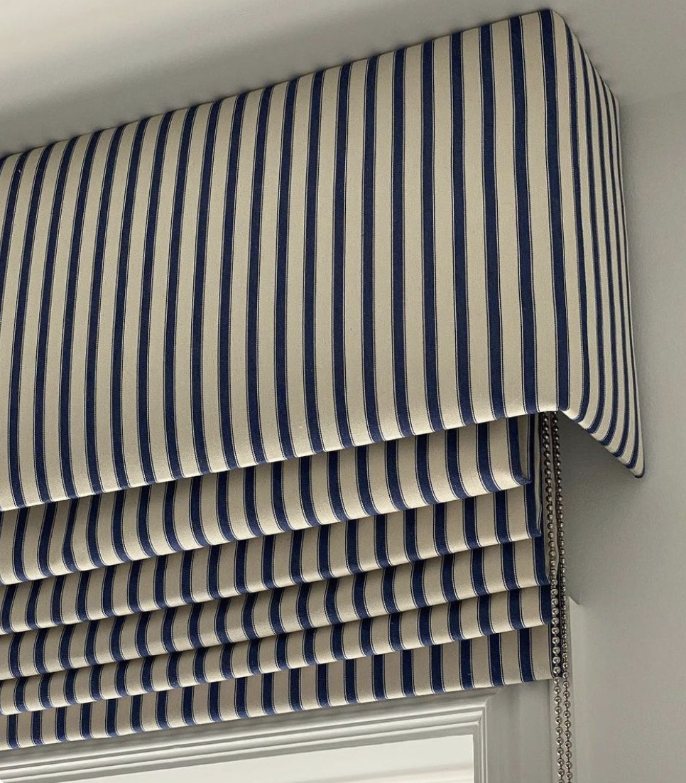 Window valance with blue and white vertical stripes and decorative beaded trim.