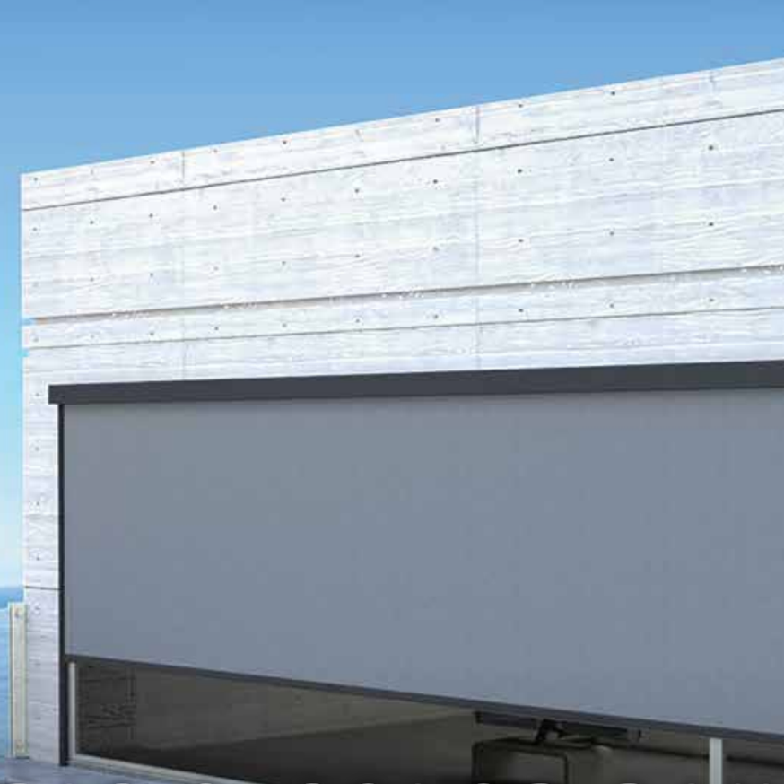 Close-up of a modern garage with a closed rolling shutter and a light gray wall, against a clear blue sky.