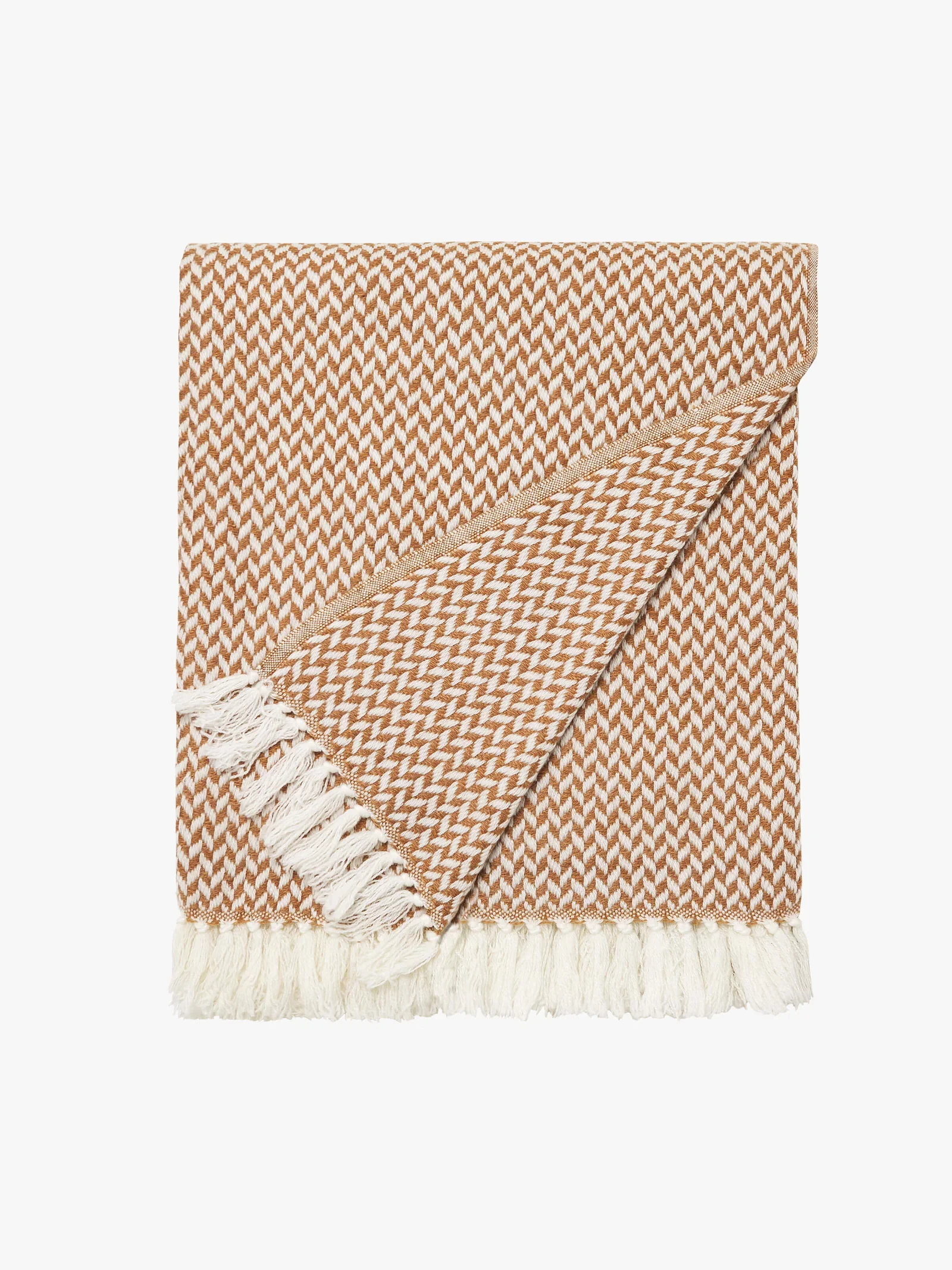 A folded beige and white patterned woven blanket with fringe edges.