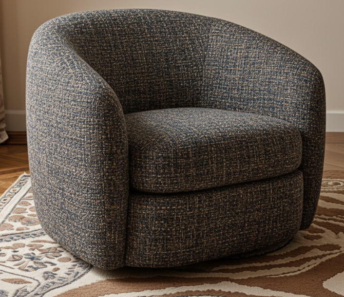 A dark gray upholstered armchair with rounded arms, placed on a patterned beige and brown area rug in a room with wooden flooring.