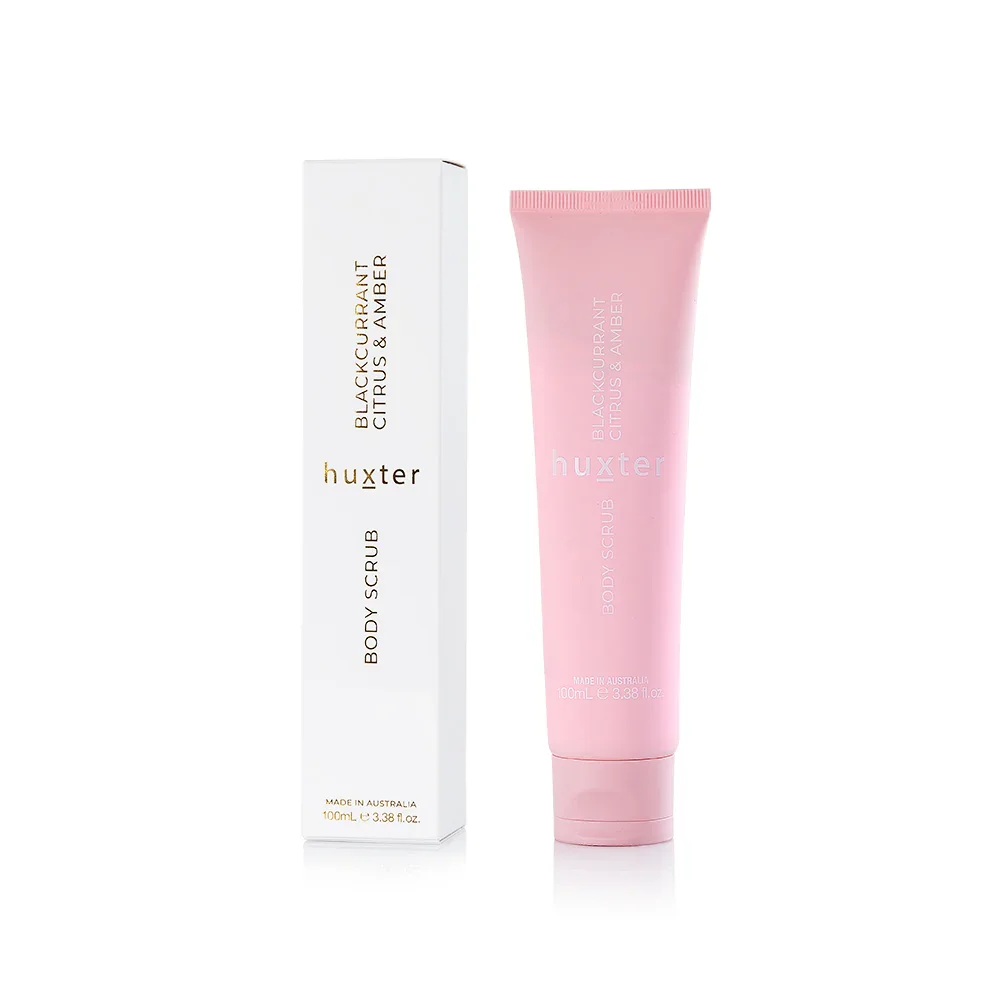 Huxter. A pink tube of blackcurrant citrus and amber body scrub next to its white packaging box.