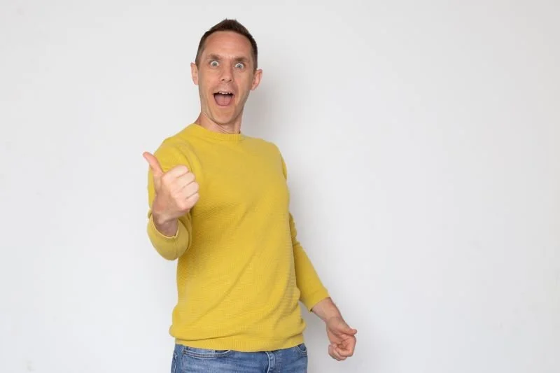 Stu McLaren, world leader in Memberships, a man wearing yellow sweater giving a thumbs-up and smiling.