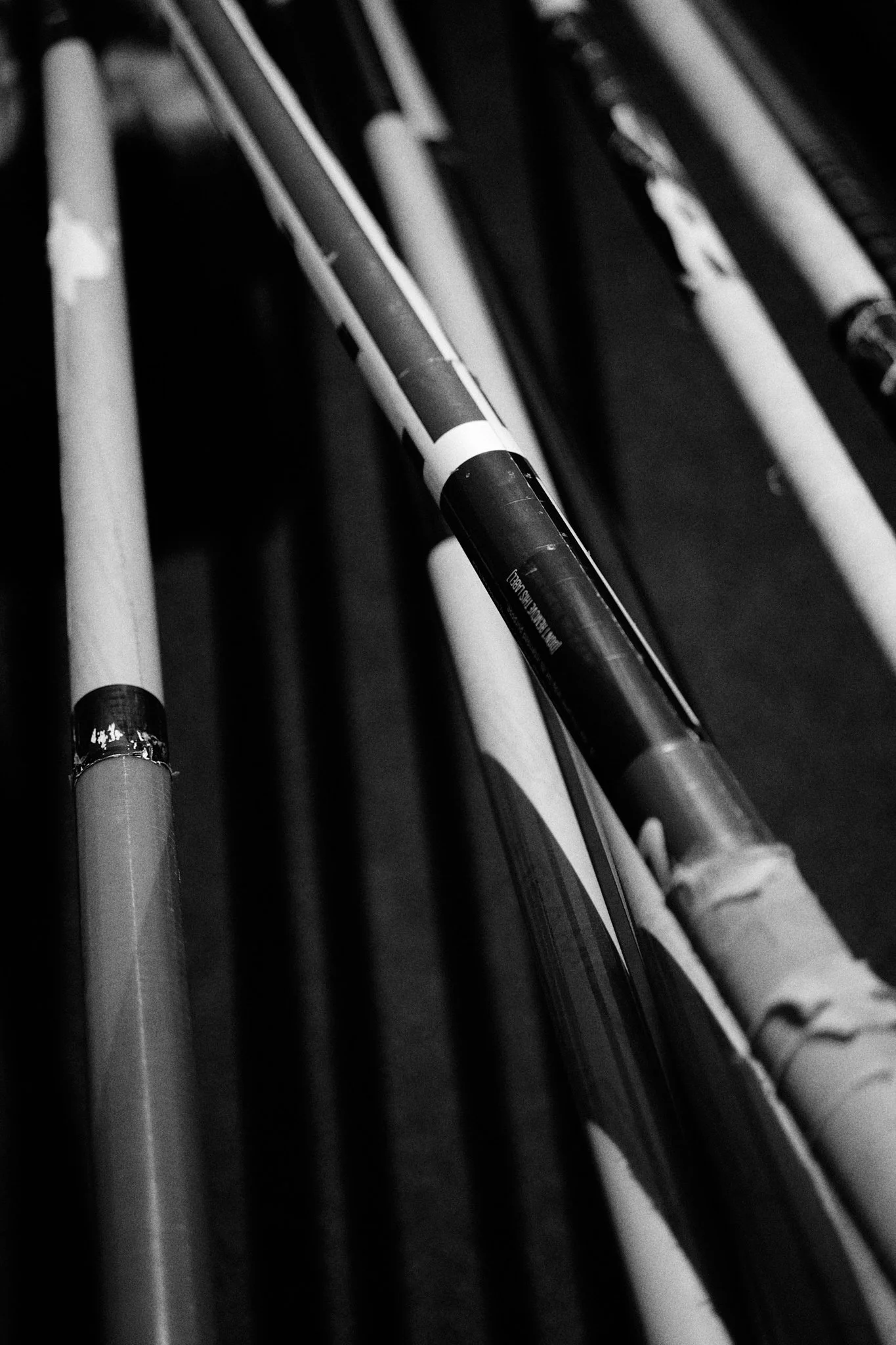 Close-up of several hockey sticks resting on a rack, in black and white.