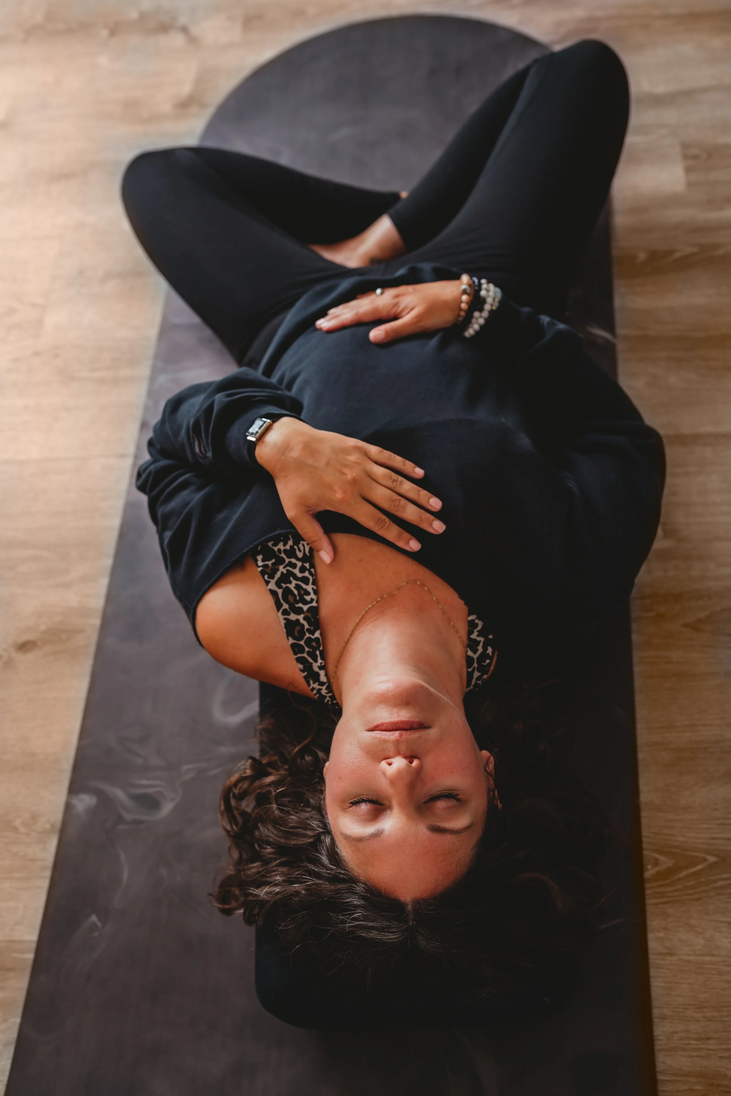 Woman meditating in a seated pose on a black yoga mat.