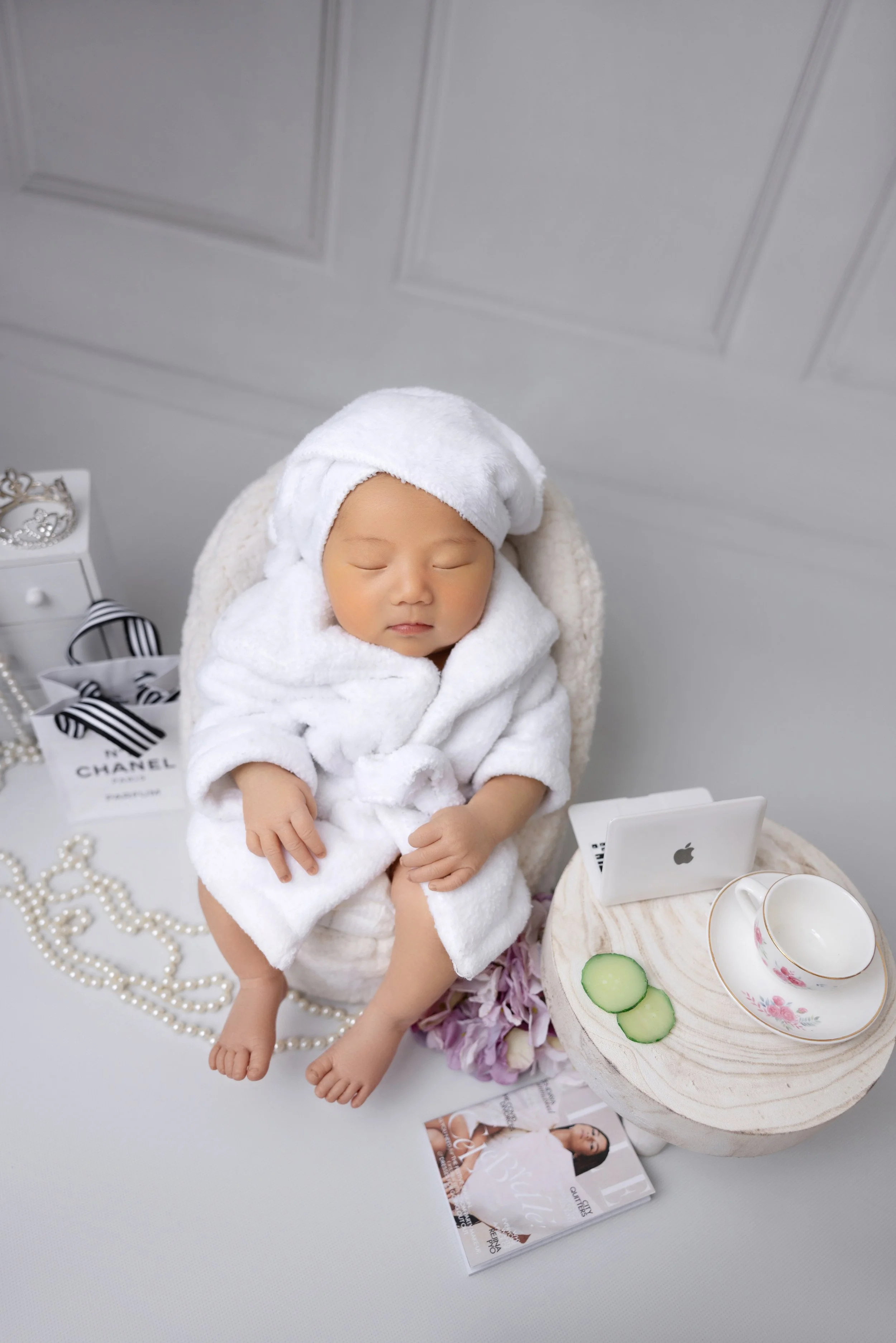 Spa Theme Newborn Photo
Unique luxury newborn session in Los Angeles — baby girl styled for a spa day with fluffy robe, towel wrap, Chanel details, pearls, and mini laptop for a glamorous touch.