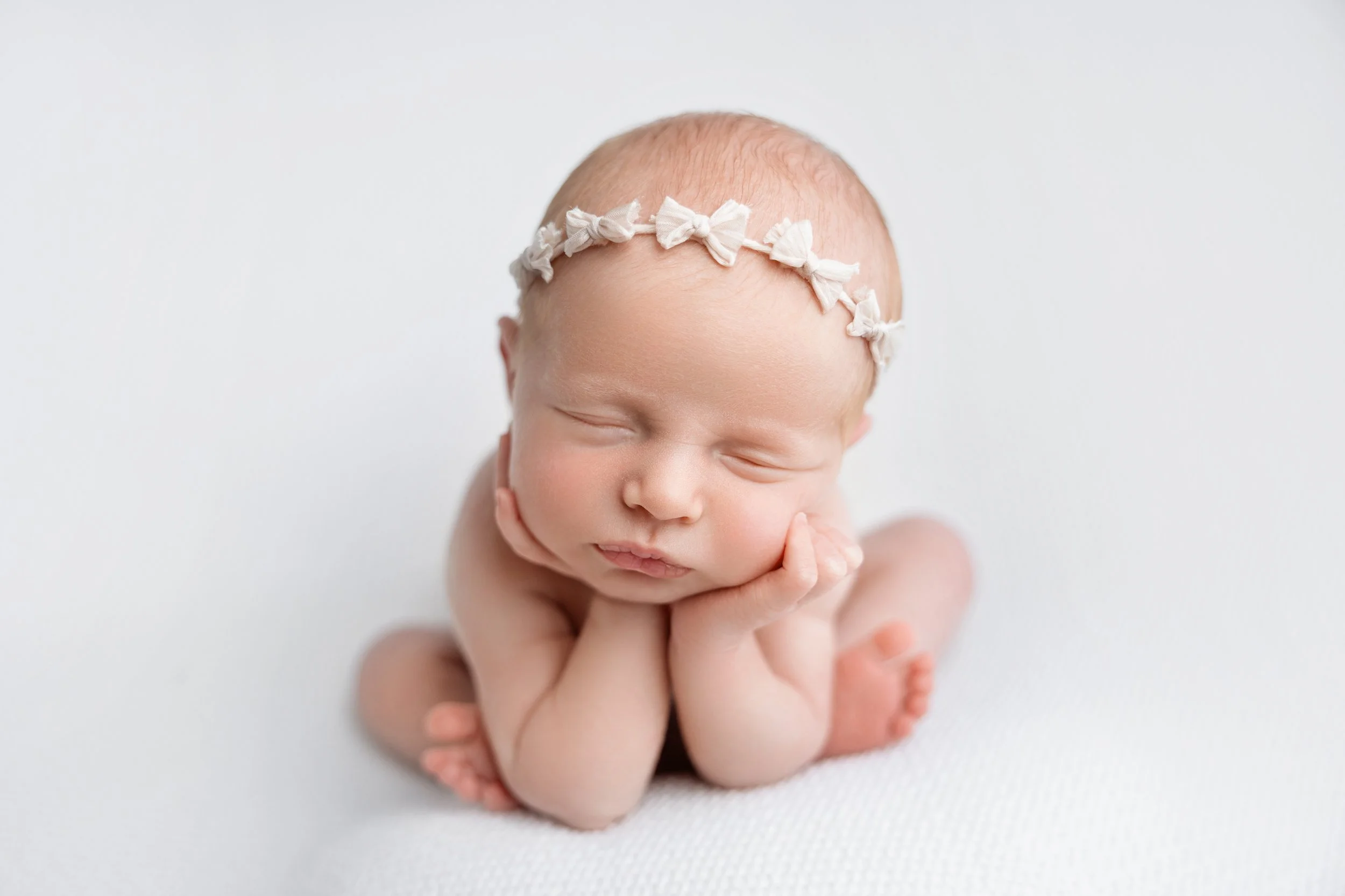 Classic froggy pose newborn session in Los Angeles — timeless baby girl portrait with delicate headband on soft white backdrop by Grethel Villate Photography.