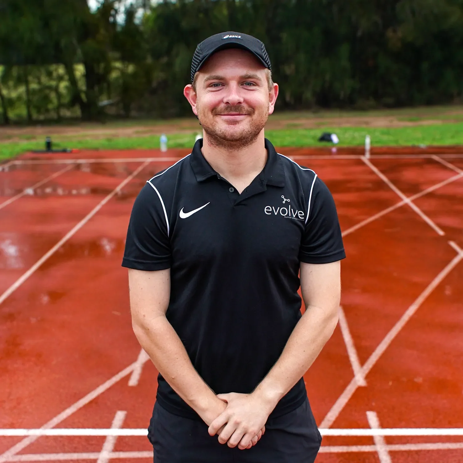 Man standing in front of running track wear a hat and evolve shirt