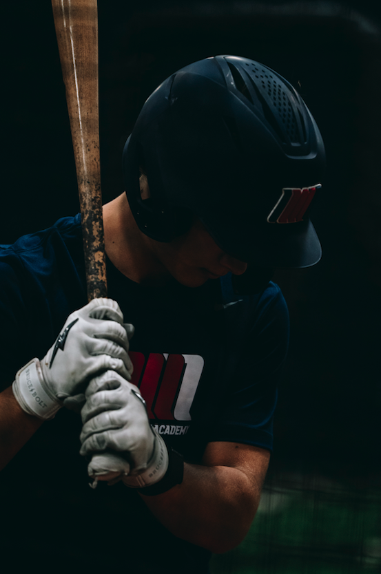 Close view of a helmeted hitter gripping a bat during baseball training