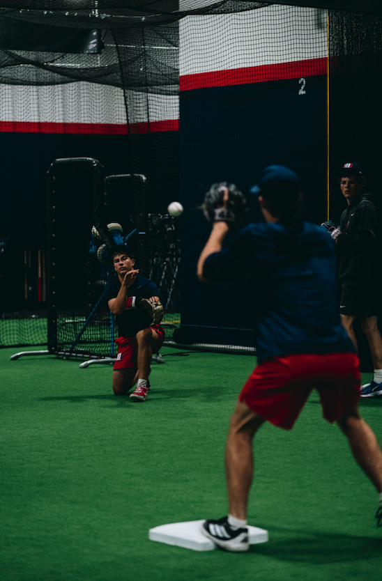 Infielders working through a fielding drill near a base on indoor turf