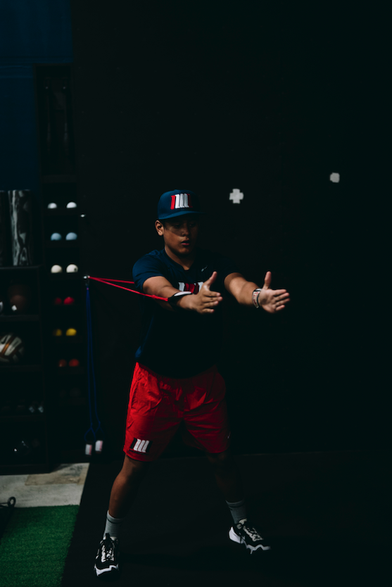 Player doing a resistance band arm care drill during baseball training