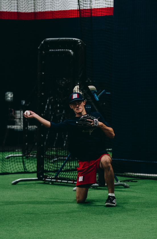 Player throwing from one knee during a Development Academy throwing drill