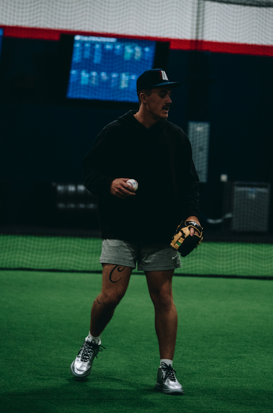 Player holding a baseball and glove at the indoor Beaverton, Oregon facility