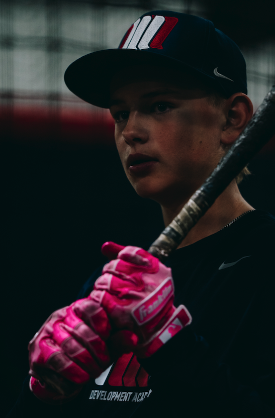 Young hitter in pink batting gloves wearing a Northwest Nationals cap