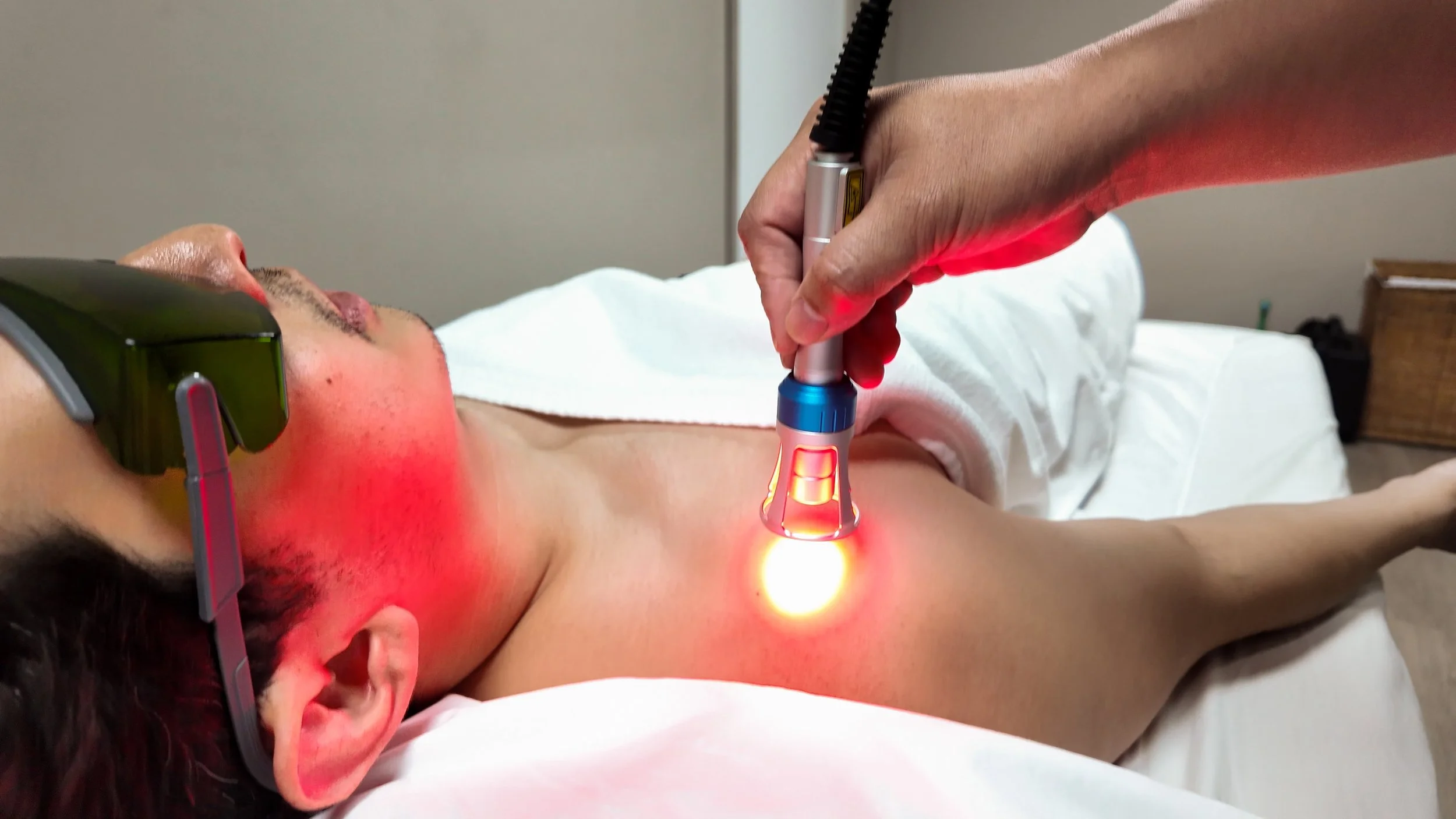 A steaming herbal compress pressed on a person's back during a massage in a dimly lit setting.