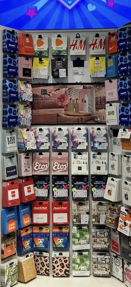 Display of gift cards and stationery including H&M, Zalando, IKEA, Media Markt, and others in a retail store.