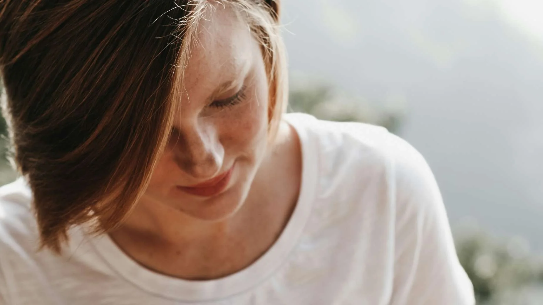vrouw kijkt naar beneden in gedachten, symbool voor zelfkritiek en innerlijke criticus