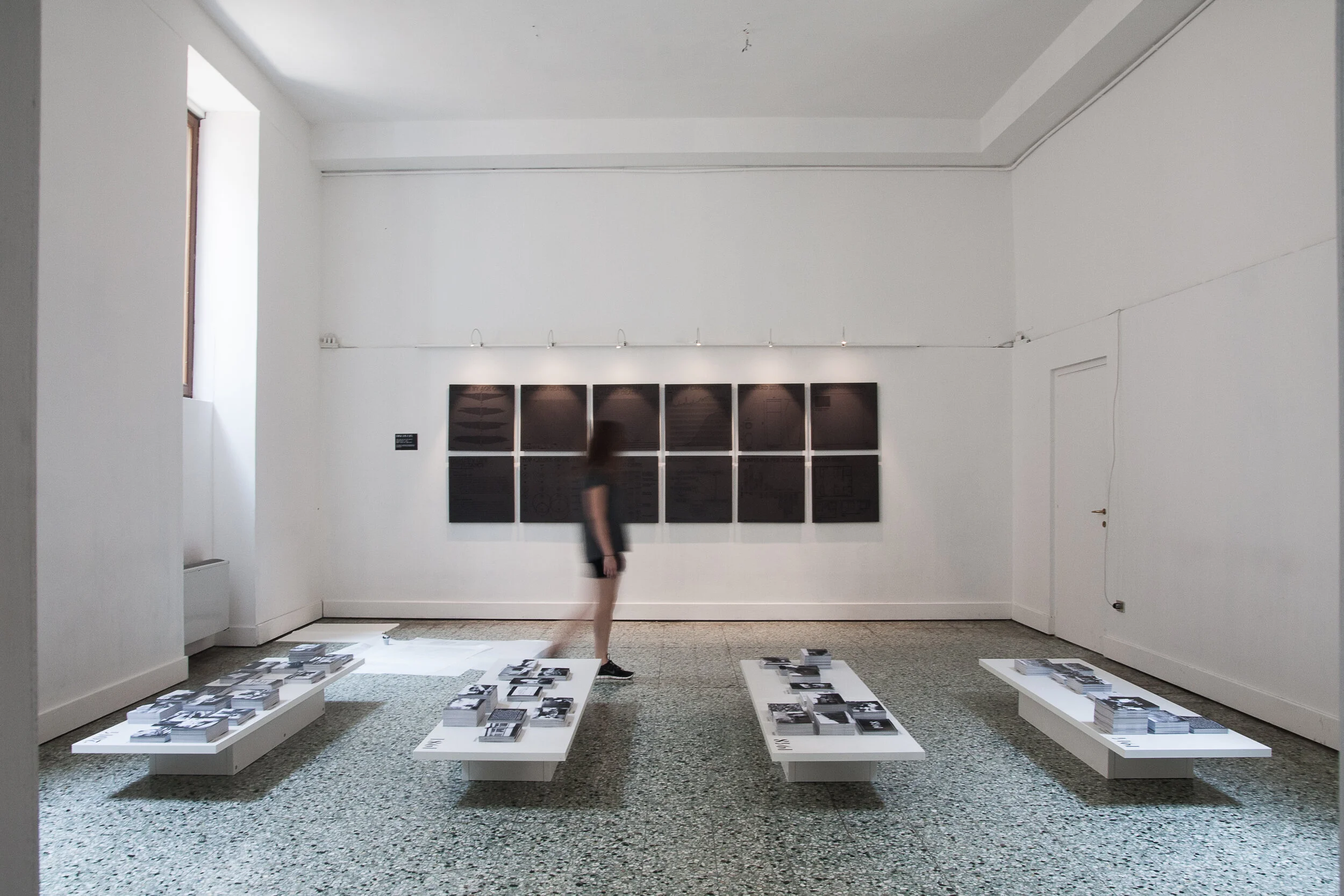 Infographics related to changing approaches to death hung on the back wall. The four tables each represented one of the years 1914, 1948, 1981 or 2014, with the postcards on them showing the sequence of spaces that people pass through on either side 