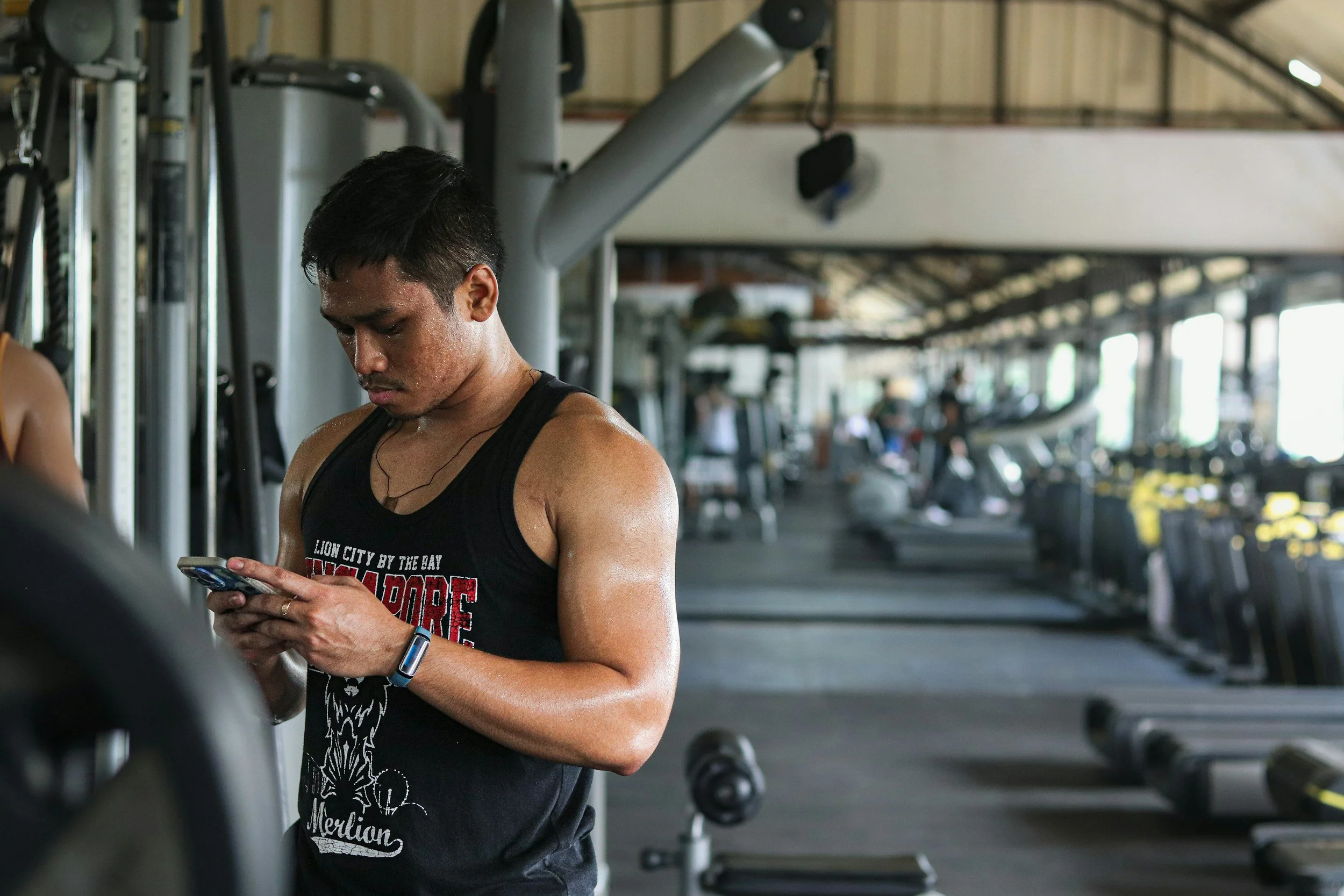 Lifter checking his online coaching program on his phone at the gym