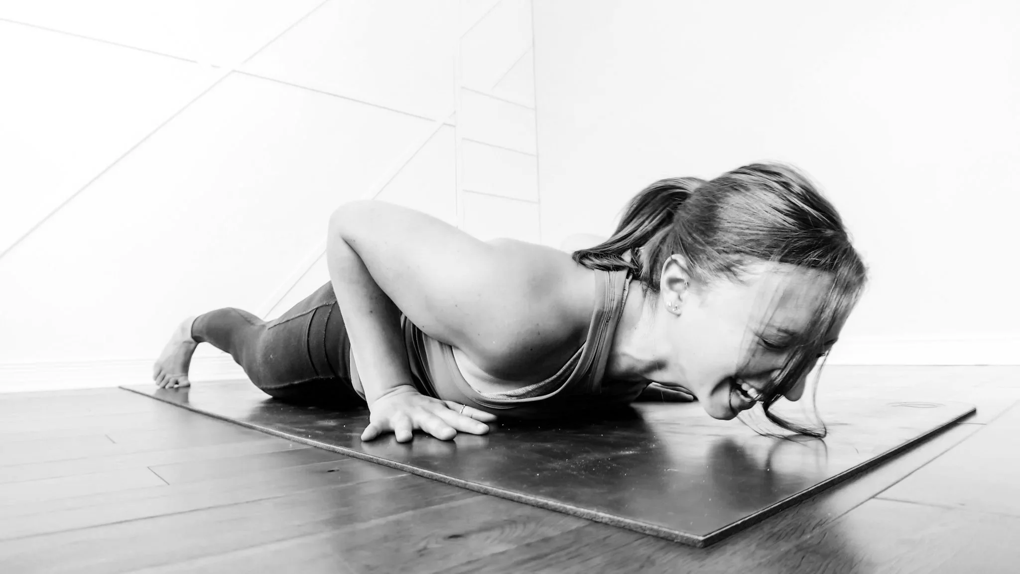 Woman performing a prone Pilates exercise on her stomach to build back strength and control