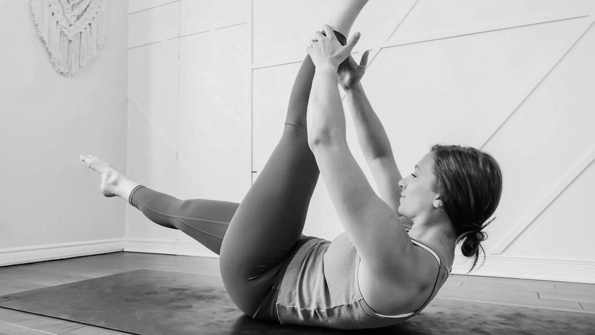 Woman lying on back with legs raised performing a Pilates core control exercise in a Toronto studio