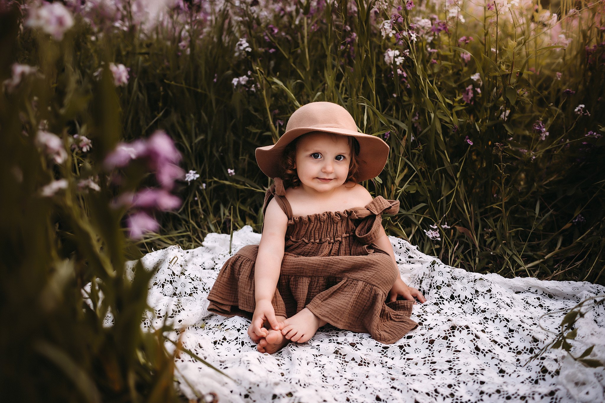 Adorable little girl in hat in purple flowers