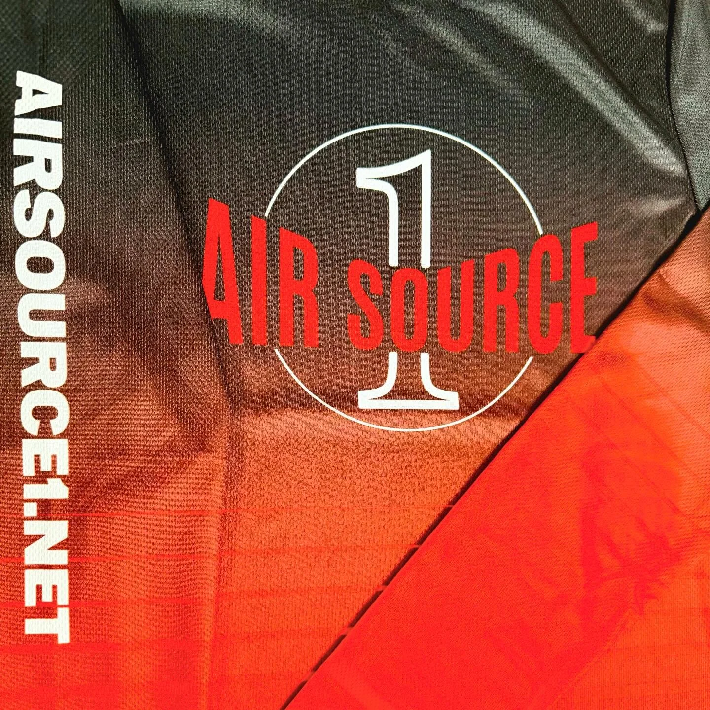 Close-up of a label on a black and orange surface, with text reading '1 AIR SOURCE' and 'AIRSOURCEINJET' in white.