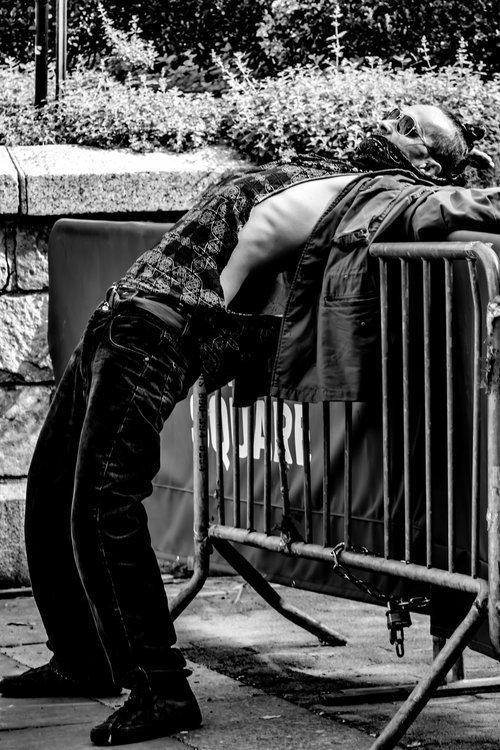 Black and white photo of a man leaning back over a metal barricade