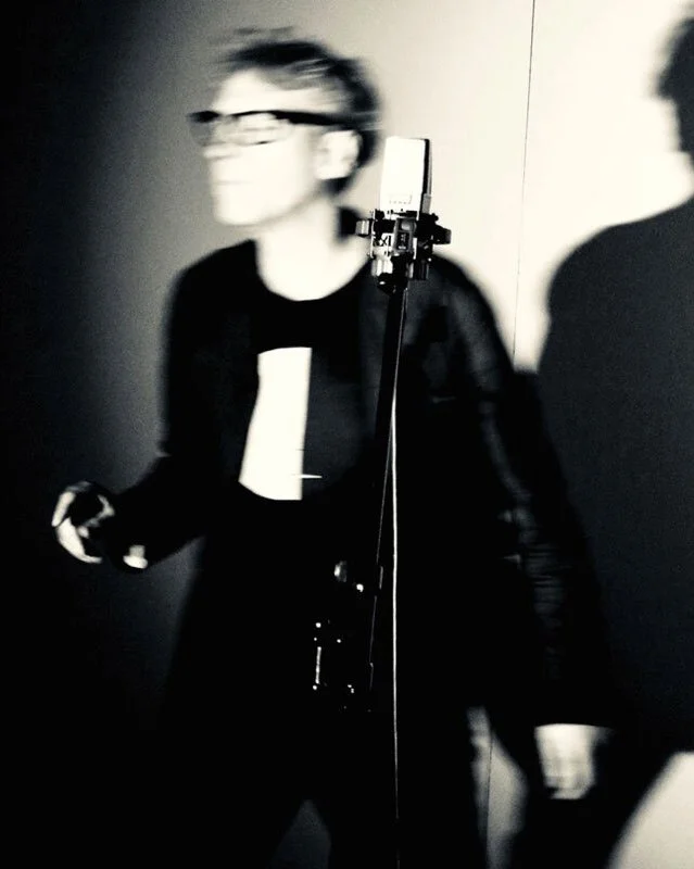 Blurry person wearing glasses in front of a microphone, black and white photo
