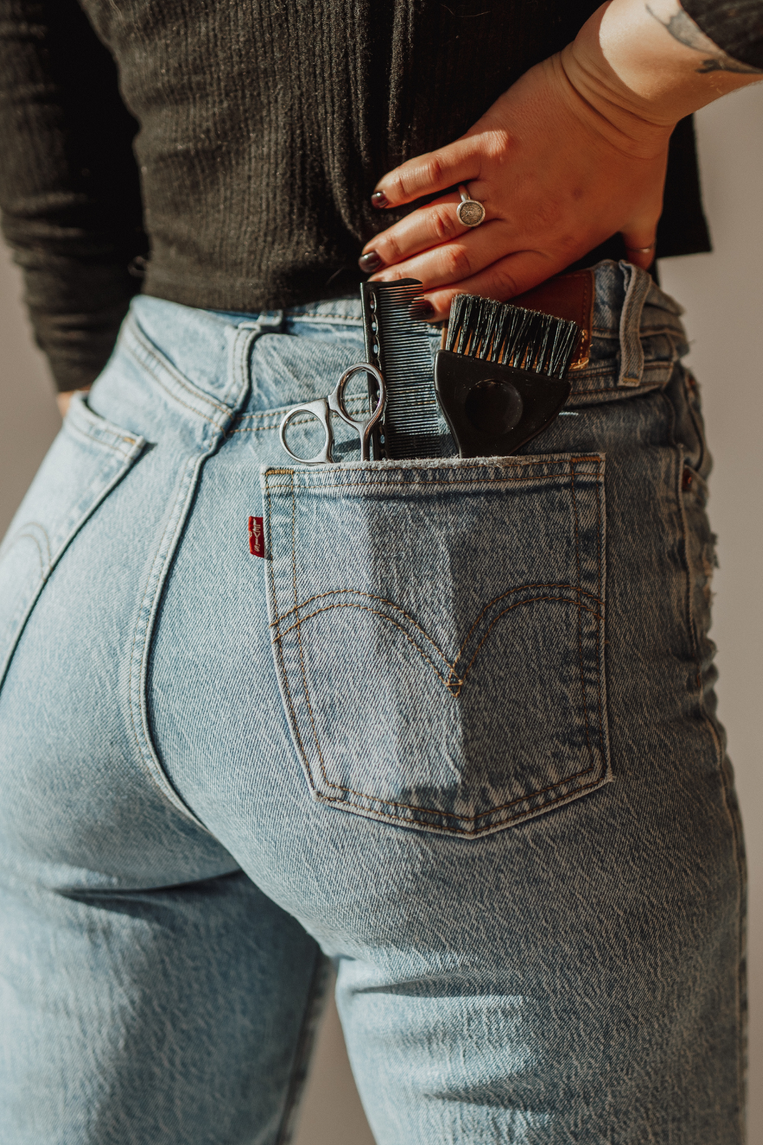 Hairbrush, pair of scissors, hair clip, and comb on a white surface, with a blurred background.