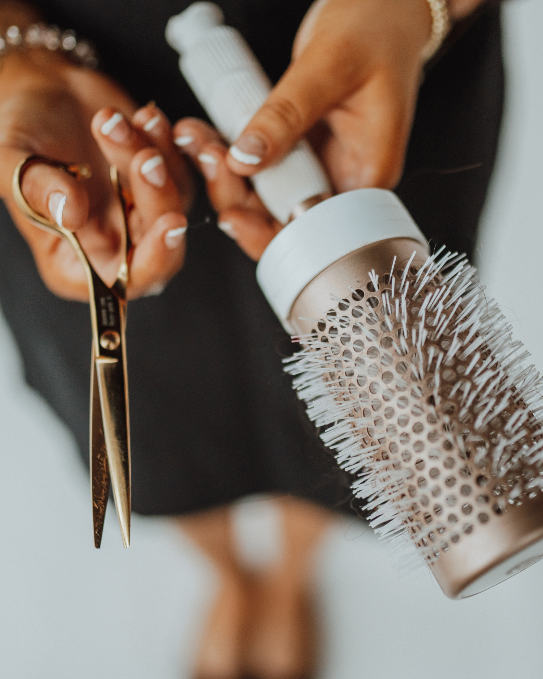 A light-colored apron on a gray surface with paint brushes in its pocket and a plant nearby.
