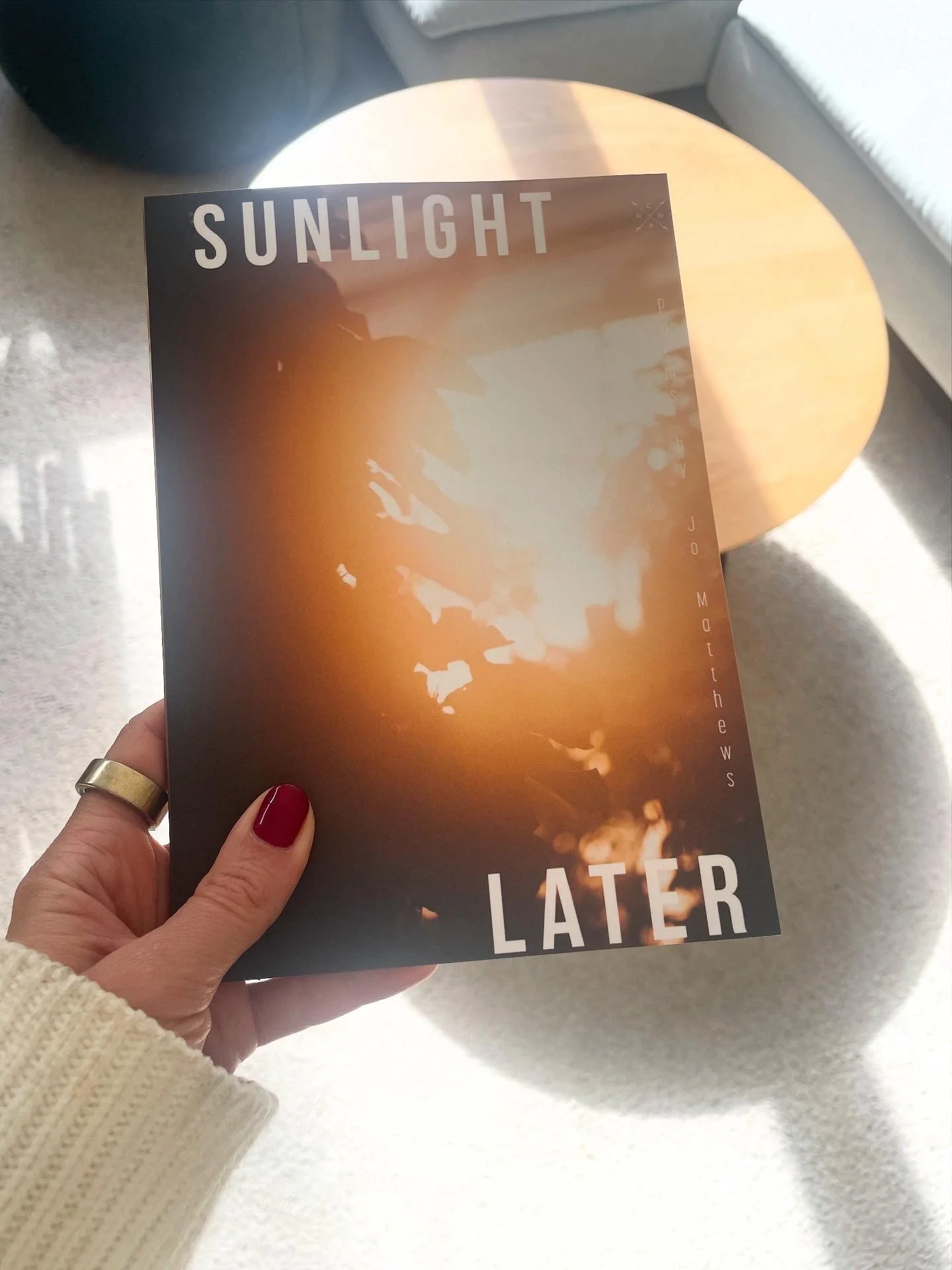 A hand holding "Sunlight Later", the debut poetry chapbook by Jo Matthews.